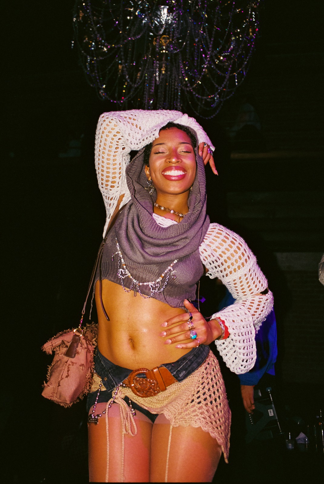 A girl in a white crochet top and shrug posing mid-event